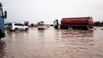 Men work to clear a stretch of the E11 heading towards Al Gharbia that is flooded after heavy rainfall in the Emirates. Sammy Dallal / The National