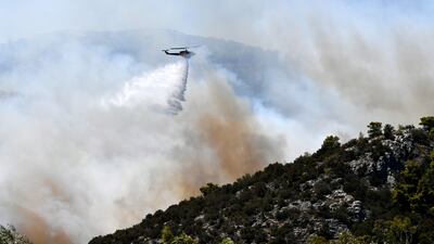 A helicopter drops water over a fire in Nea Makri, east of Athens. AP
