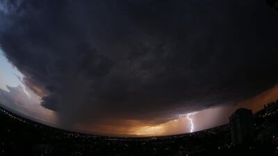 In this photo taken with a fisheye lens, a massive storm cloud packing high winds, hail and heavy rains sweeps over downtown Denver as lightning strikes on the horizon on Monday. David Zalubowski / AP
