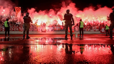 Stewards and security personnel watch as Red Star supporters light flares during the Serbian Cup semi-final football match at Partizan Belgrade on Wednesday, June 10. Partizan won the match 1-0. AFP