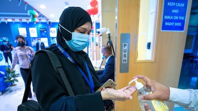 A teacher's hands are sanitised, following a temperature check in the lobby, before she enters a classroom at Gems United Indian School, Abu Dhabi. Victor Besa / The National