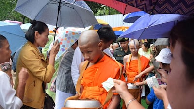 Novice monk Ekarat 'Bew' Wongsukchan, centre, and Duganpet 'Dom' Promtep, receive offerings after their participation in a Buddhist novice monk ordination ceremony. EPA