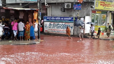 People wade past a road turned red after blood from sacrificed animals on Eid Al Adha mixed with water from heavy rainfall in Dhaka, Bangladesh. (AP Photo)