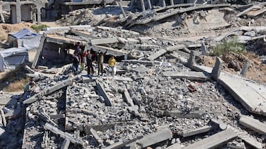 Displaced children stand on the rubble of destroyed houses as they watch food being prepared on the rooftop in the northern Gaza Strip. AFP