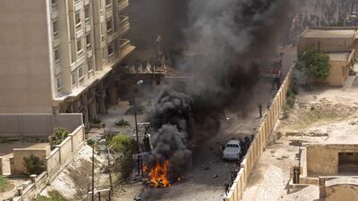 Egyptians gather around a burning vehicle at the site of a bomb attack in the northern port city of Alexandria, which hit a convoy of the city's security chief. AFP