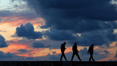 Palestinian youths walk next to the beach during sunset in Gaza City. Mohammed Saber / EPA