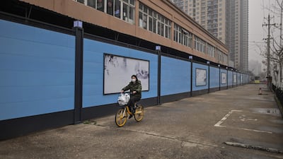 A woman cycles past the closed Huanan Seafood wholesale market in Wuhan on January 23, one year after the city went into lockdown to curb the spread of the coronavirus. AFP
