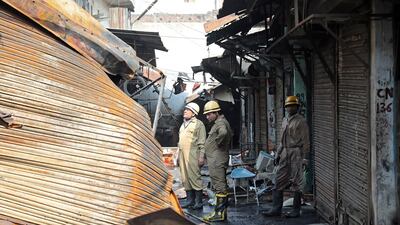 Firefighters looks at debris at a burnt market near Gokulpuri metro station area after clashes in New Delhi, India. EPA