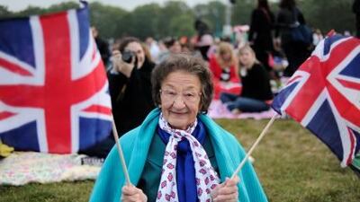 A royal fan holds British Union Jack flags as people gather to watch the wedding in Hyde Park in central London. AFP