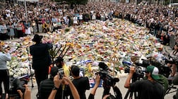 Mourners stand together near tributes at the Bondi Pavilion in memory of the victims of a shooting at Bondi Beach, in Sydney on December 16, 2025. Australia's leaders have agreed to toughen gun laws after attackers killed 15 people at a Jewish festival on Bondi Beach, the worst mass shooting in decades decried as antisemitic "terrorism" by authorities. (Photo by Saeed KHAN / AFP)