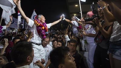 Top, Lee Hsien Loong, Singapore’s prime minister and the leader of the People’s Action Party, celebrates after its landslide election win earlier this month. Above, his father, Prime Minister Lee Kuan Yew, visits the newly built Commonwealth Close Estate in 1965. Nicky Loh / Bloombeg