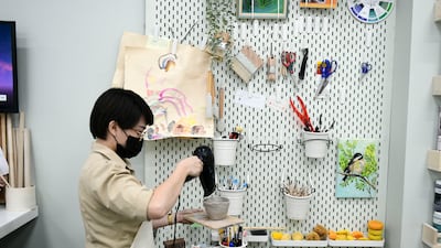 Shy Lee, teaching assistant, blow dries a clay cup.