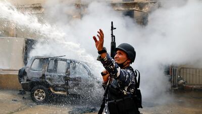 A police officer gestures to firefighters as they extinguish a police car that was set on fire by anti-government protesters, in the northern city of Tripoli, Lebanon, Tuesday, April 28, 2020. Hundreds of angry Lebanese took part Tuesday in the funeral of a young man killed in riots overnight in Tripoli that were triggered by the crash of Lebanon's national currency that sent food prices soaring. (AP Photo/Bilal Hussein)