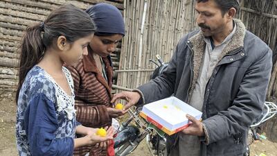 Dharam Veer Solanki, the leader of the Pakistani Hindu community in Majnu Ka Tilla in New Delhi distributing sweets to children. Taniya Dutta for The National