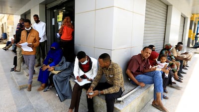People wait outside a currency exchange bureau in Sudan's capital Khartoum. The North African country is inching closer to debt relief after a second IMF review. Reuters.