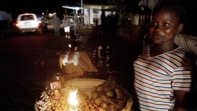 A Sierra Leonean street vendor lights her stand with a candle in Freetown. ISSOUF SANOGO / AFP