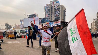 An anti-government protester poses for a picture while holding a national flag in Baghdad, Iraq. AP