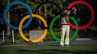 A woman takes a selfie in front of the Olympic Rings in Tokyo. Getty