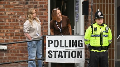 Election officials and a policeman stand outside a polling station for the Makerfield by-election, in Hindley, north-west England. AFP