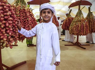 Saif Al Mazrouei, 6, beside the heaviest date fruit clumps of the festival. Victor Besa / The National.