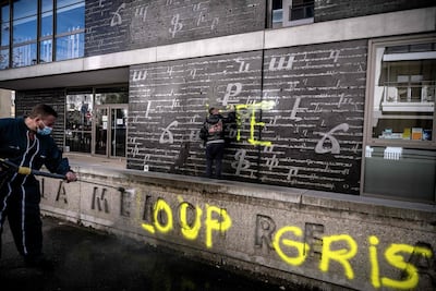 Men clean an outside wall of the National Armenian Memorial Centre in Decines-Charpieu, near Lyon, on November 1, 2020 where pro-Turkish graffiti tags have been painted overnight. Inscriptions read "RTE" which can refer to Turkish President Recep Tayyip Erdogan and "Grey Wolf" (Loup Gris), the name of an ultra-nationalist movement in Turkey. AFP
