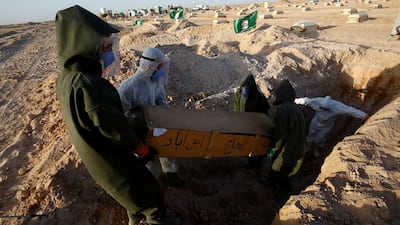 Members of the PMF, who volunteered to work at the cemetery, wear protective suits as they bury the coffin of a man who passed away due to coronavirus disease. REUTERS