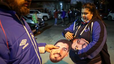 Fans of Nacional team are given Luis Suarez masks outside the stadium in Montevideo. EPA