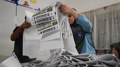 Election workers gather parliamentary election ballots after the polls closed in Baghdad on November 11, 2025. AP