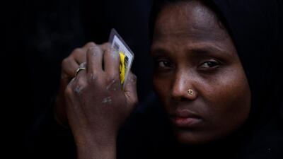 A Rohingya refugee woman holds her identity and work cards after moving mud from the riverbed to help raise the ground level of the camp, in preparation for monsoon season, in Shamlapur refugee camp in Cox's Bazaar, March 25, 2018. Clodagh Kilcoyne / Reuters