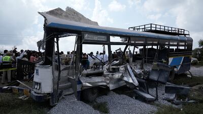 People stand next to the passenger bus after a lorry loaded with concrete stone chips rammed into it at Chevalla in southern state of Telangana, India. AP