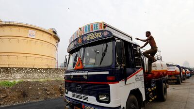 A man climbs an an oil tanker parked outside a fuel depot in Mumbai, India. The new goods and services tax has been painful for some. Danish Siddiqui/Reuters