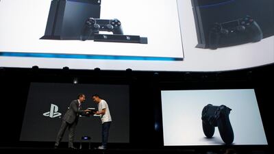 Andrew House, president and group chief executive officer of Sony Computer Entertainment Inc., left, passes the company's PlayStation 4 console to a designer during the Sony Corp. E3 media event in Los Angeles, California, U.S., on Monday, June 10, 2013. Sony Corp. took the wraps off the PlayStation 4, its first new console in seven years, promising original content and fresh titles will revitalize demand and spark a comeback for the video-game industry it once dominated. Photographer: Patrick T. Fallon/Bloomberg *** Local Caption *** Andrew House 1237341.jpg