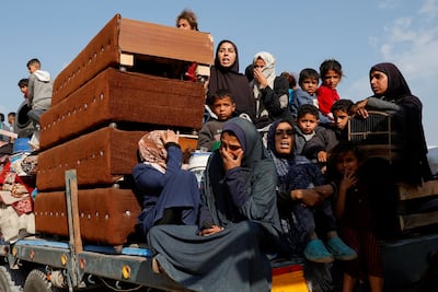 Palestinians ride on the back of a truck as they flee their homes after the Israeli army issued evacuation orders for a number of neighborhoods in Rafah in the southern Gaza Strip on March 18, 2025. Reuters
