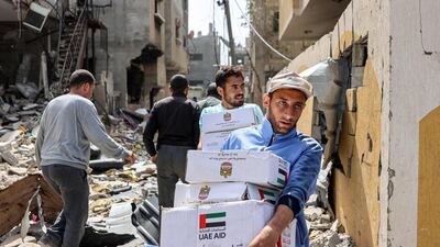 Men carry boxes of aid through the rubble of damaged buildings after the airdrop