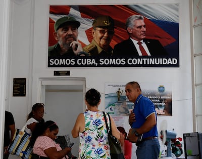 People work at an office of the Ministry of Finance and Prices underneath a framed poster of Cuba's late president Fidel Castro, his brother, former president Raul Castro and President Miguel Diaz-Canel. Reuters