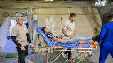 Healthcare staff wheel a patient into an assessment area shortly after arrival from Gaza at the docked vessel in Egypt. Photo: Wam