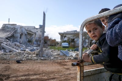 Displaced Syrian boys look out from the back of their family truck as they visit their home in the village of Al Nayrab in northwestern Syria on March 29, 2020. AFP