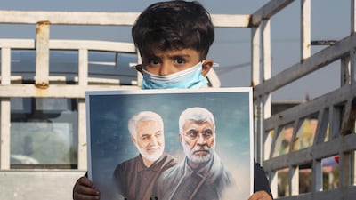 An Iraqi boy carries the portraits of Iraqi commander Abu Mahdi al-Muhandis and Iranian Revolutionary Guards commander Qasem Soleimani during a demonstration in Baghdad's western Shoala neighbourhood. AFP