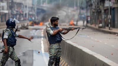 A policeman aims his weapon at protesters during a curfew imposed after violent protests. AP
