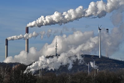 A Uniper coal-fired power plant and a BP refinery steam beside a wind generator in Gelsenkirchen, Germany. AP