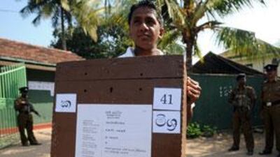 Protected by soldiers, a Sri Lankan election worker carries a ballot box for distribution from a central station in Colombo yesterday.