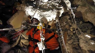 Rescuers peek under rubble to talk to trapped survivor Manuel Lora at the site of a four-storey building collapse in Port-au-Prince, Haiti, on Wednesday, January 13, 2010.