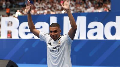 French forward Kylian Mbappe waves to the fans during a first appearance as a Real Madrid player at the Santiago Bernabeu Stadium in Madrid on July 16, 2024, after signing his new five-season contract. Still celebrating Spain's Euro 2024 triumph, Real Madrid fans have even more to cheer this July 16, 2024, as French superstar Kylian Mbappe is officially presented to a packed-out Santiago Bernabeu stadium. (Photo by Pierre-Philippe MARCOU / AFP)