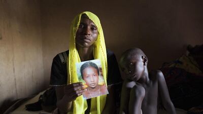 Rachel Daniel, 35, holds up a picture of her abducted daughter Rose Daniel, 17, as her son Bukar, 7, sits beside her at her home in Maiduguri in this May 21 file photo. Joe Penney / Reuters