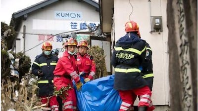 Members of the Chinese International Search and Rescue Team carry a victim's body in the quake-shaken city of Ofunato, Japan.