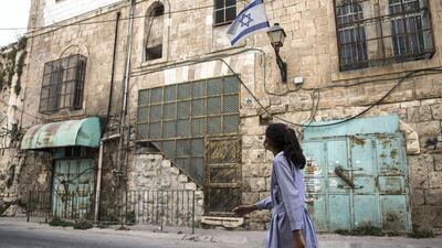 A Palestinian school girl walks along a Hebron street where Palestinian shops have long since been welded shut by the Israeli military .