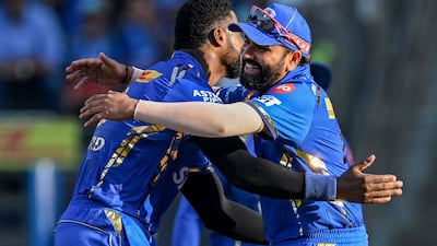 Mumbai Indians' Romario Shepherd celebrates with his teammate Rohit Sharma, right, after taking the wicket of Delhi Capitals' David Warner. AFP