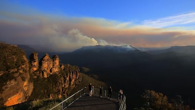 The Three Sisters rock formation is visible as people watch smoke from the Green Wattle Creek fire from Echo Point lookout in Katoomba, New South Wales, Australia. EPA