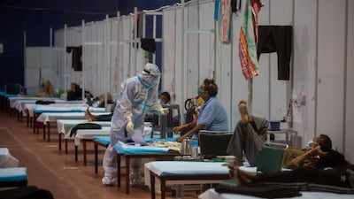 A health worker takes the temperature of a patient at a makeshift Covid-19 care center at an indoor sports stadium in New Delhi. AP Photo