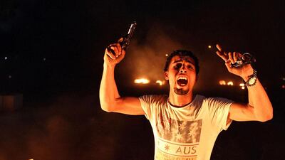 An armed Libyan demonstrator shouts slogans as they burn tyres blocking a main street in the eastern Libyan coastal city of Benghazi during a protest against the extended mandate of the General National Congress. Abdullah Doma / AFP
